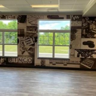 A spacious room with large windows and a decorative mural on the wall.