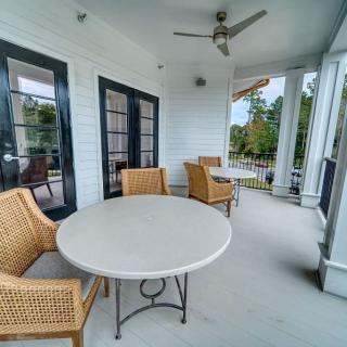 A cozy porch with a round table and wicker chairs, featuring a ceiling fan and surrounded by French doors.