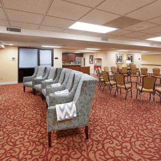 A spacious conference room with upholstered chairs and red patterned carpeting.
