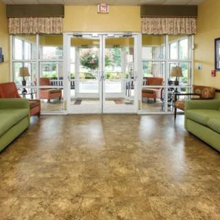 A spacious lobby with green sofas, large windows, and glass doors leading outside.