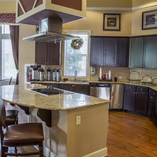 A modern kitchen featuring a central island with granite countertops, dark wood cabinetry, and stainless steel appliances.