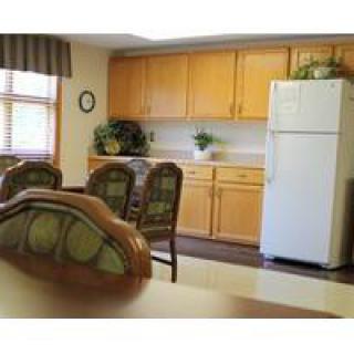 A cozy kitchen and dining area with wooden cabinets, a refrigerator, and a dining table with chairs.