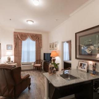 Cozy living room with elegant decor, featuring a chair, lamps, and framed artwork.