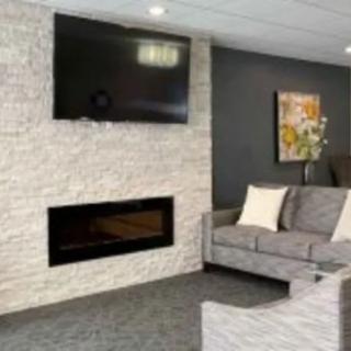 A modern living room with a fireplace, TV, and a grey couch.