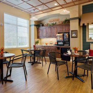 A cozy cafe interior with tables, chairs, and a kitchen area.