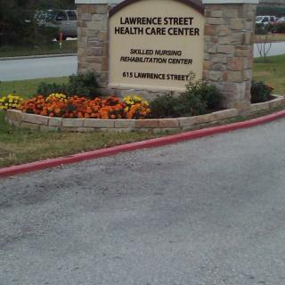 Entrance sign for Lawrence Street Health Care Center with a flowerbed.