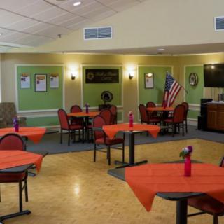 A dining area with tables covered in orange tablecloths, decorated with small vases and an American flag.