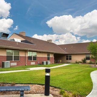 A modern house with a well-maintained lawn under a blue sky with clouds.