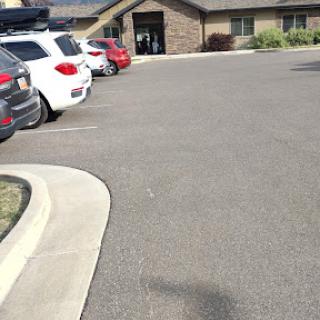 A view of a parking lot with several cars parked in front of a building.