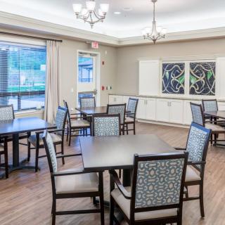 An elegant dining room with neatly arranged tables and chairs, featuring stylish lighting and wall decorations.