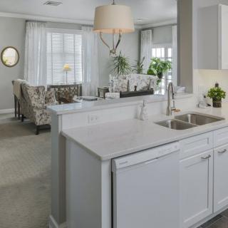 A modern kitchen with white cabinetry opens up to a spacious living area.