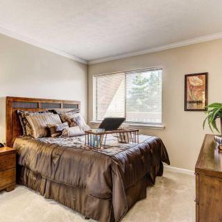 A cozy bedroom with a wooden bedframe and large window.