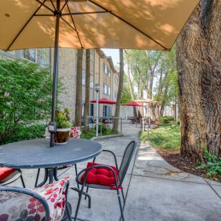 A cozy outdoor patio area with seating, umbrellas, and lush greenery.