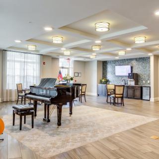 A spacious and elegantly designed living room featuring a grand piano, comfortable seating, and modern lighting fixtures.