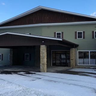 A two-story building with a covered entrance, surrounded by snow under a clear blue sky.