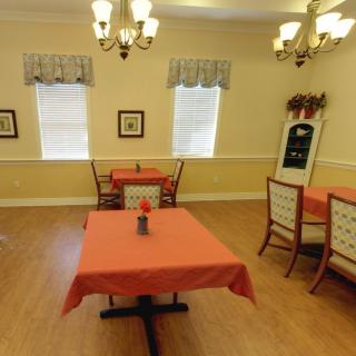 A cozy dining room with tables and chairs, decorated with chandeliers and curtains.