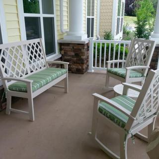 Outdoor porch area with white lattice furniture and green cushions.