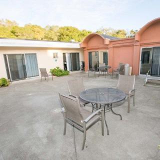 A spacious patio with outdoor furniture, including a table and chairs, set in the backyard of a house featuring sliding doors.