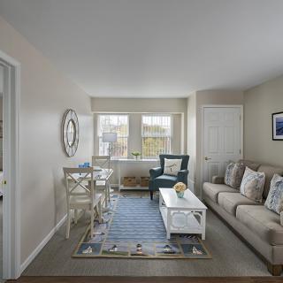A cozy living room with a sofa, armchair, and a coffee table beside a large window.