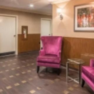 A cozy lobby area featuring vibrant pink chairs and a framed artwork on the wall.