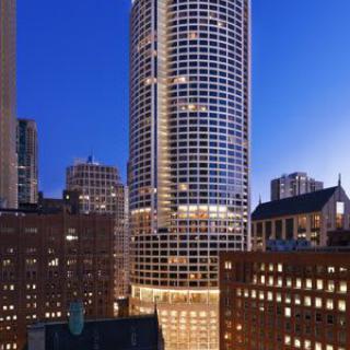 A tall skyscraper illuminated at night in a bustling cityscape.