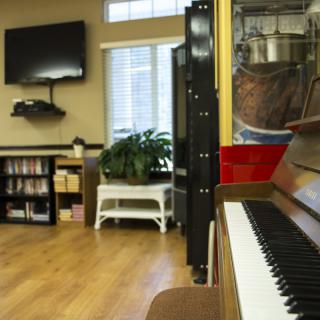 A cozy living room with a piano, television, and bookshelf.
