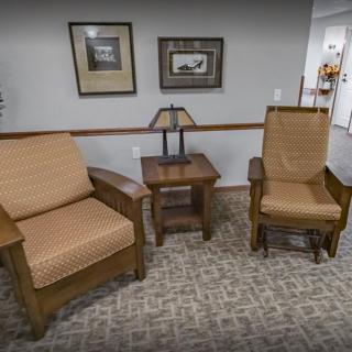 A cozy seating area featuring two chairs and a table with a lamp in between.