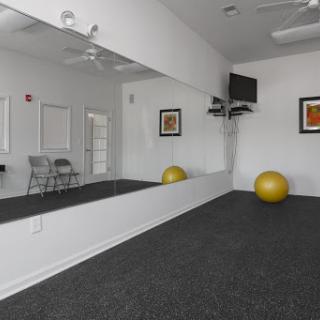 A spacious exercise room featuring a large mirror, a gym ball, and modern decor.