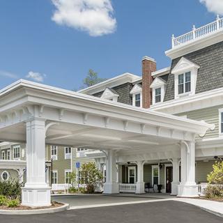 A large building with a covered entrance and classic architectural features on a sunny day.