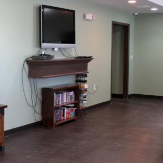 A modern living room featuring a wall-mounted television and a small bookshelf with video games.