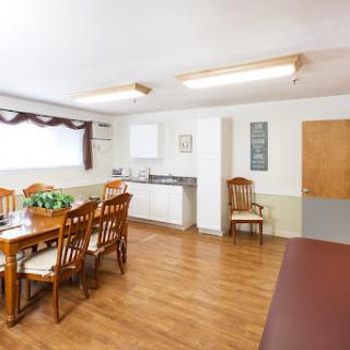 A cozy dining area featuring wooden furniture and a kitchen space, designed for casual gatherings.