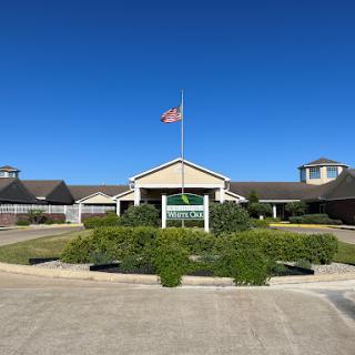 A welcoming entrance to a facility with a flag flying under a clear blue sky.