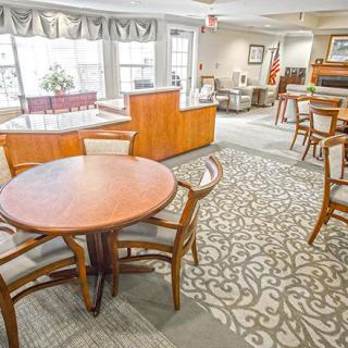 A cozy, spacious lounge area with tables and chairs set on a patterned carpet.