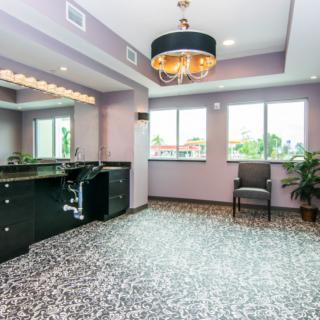 A modern interior room with a chandelier, large mirrors, and ample natural light from the windows.