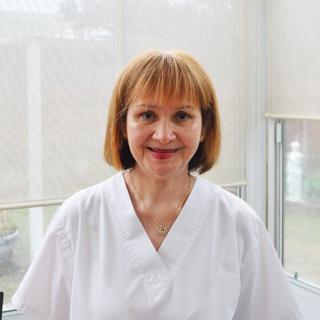A smiling healthcare professional in a white uniform indoors.