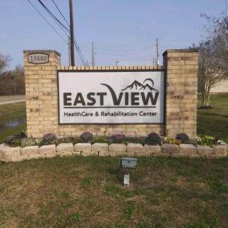 Sign for East View Healthcare & Rehabilitation Center displayed outdoors with brick pillars.