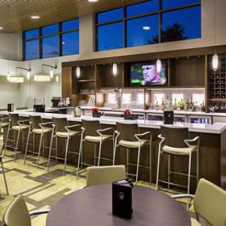 A modern bar and dining area with high chairs and a television, set in an elegant interior.