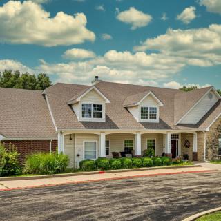 A suburban house with a spacious driveway under a partly cloudy sky.
