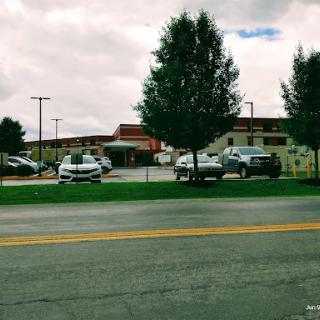 A view of a building with several cars parked in front, set against a cloudy sky.