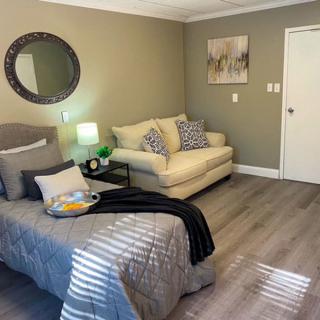 A cozy bedroom with a stylish bed and a comfortable sofa, complemented by decorative items like a mirror and artwork.