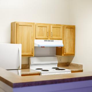 A compact kitchen with wooden cabinets and a white stove.