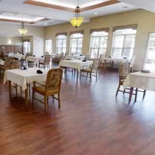 A spacious dining room with neatly arranged tables and chairs, accented by large windows.
