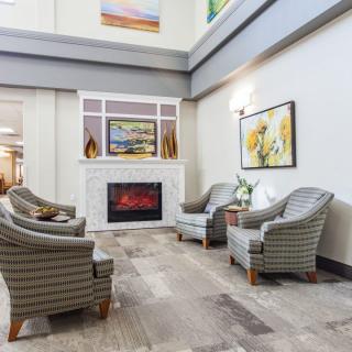 A modern lobby seating area with upholstered chairs and a decorative fireplace.