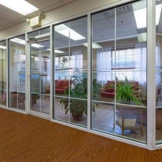 An office lobby with glass walls, featuring comfortable seating and indoor plants.