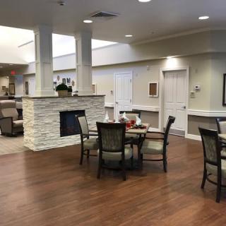 A cozy dining area with a central fireplace and elegant seating arrangements on hardwood flooring.