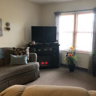 A cozy living room with a sofa, TV on a stand, and sunlight streaming through the window.