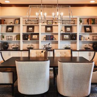 A stylish dining room with a modern chandelier and bookshelves in the background.