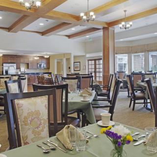 Elegant dining area with neatly arranged tables and chairs under ornate chandeliers.