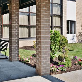 A garden area with a swing next to a building featuring tall windows and brick pillars.