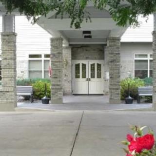 A building entrance with double doors, surrounded by greenery and flowers.